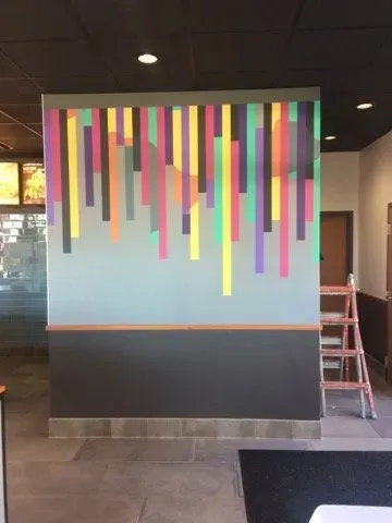 A wall in a restaurant with colorful stripes on it