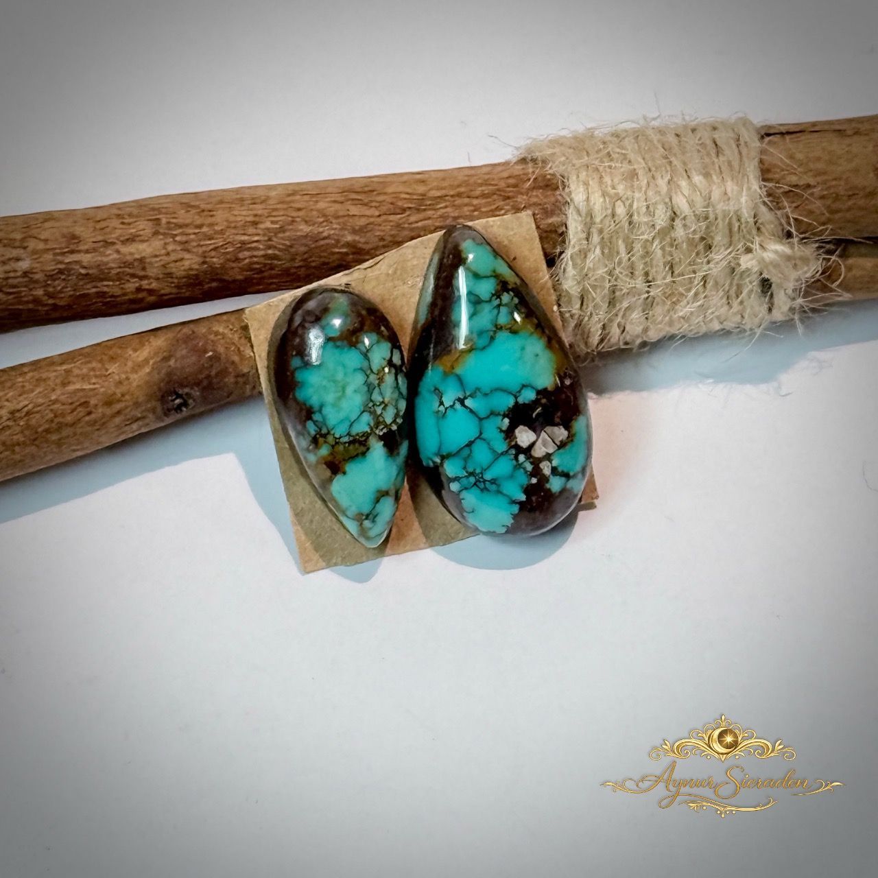 Kingman turkoois cabochon paar op houten tak – blauwgroene steen met natuurlijke matrix, handgeslepen