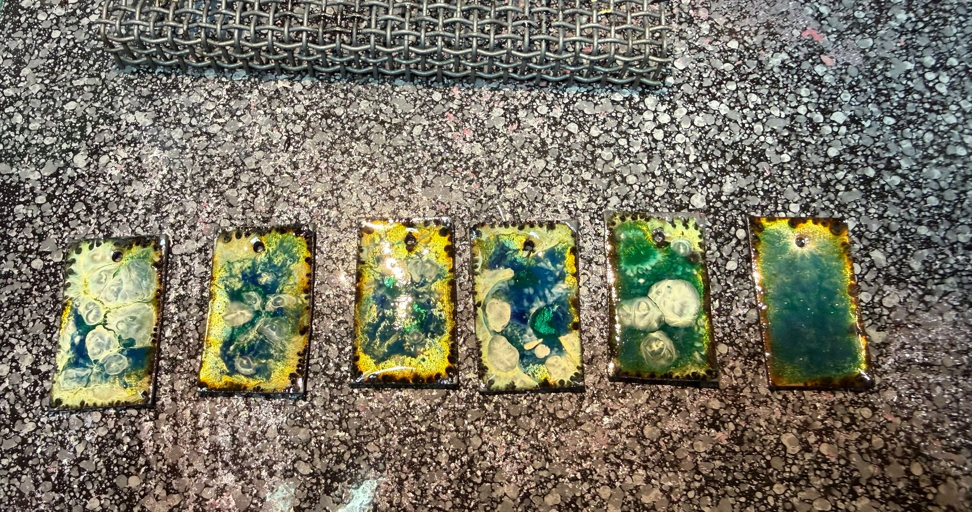 Resultaat van emaille experiment op koperplaatjes met organische patronen en kleurverloop – Aynur Sieraden