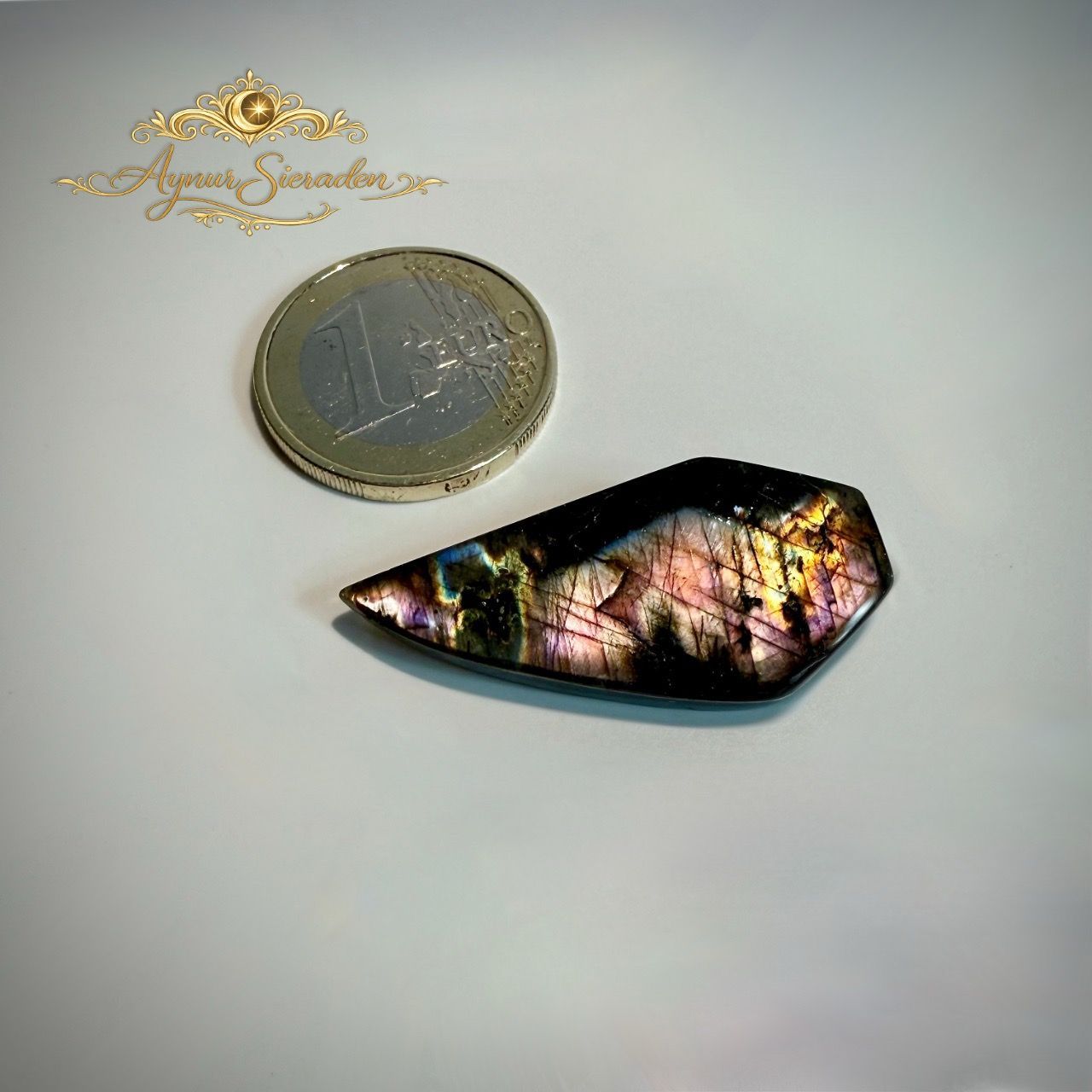 Unieke labradoriet steen met iriserende roze-gouden kleuren en organische vorm.