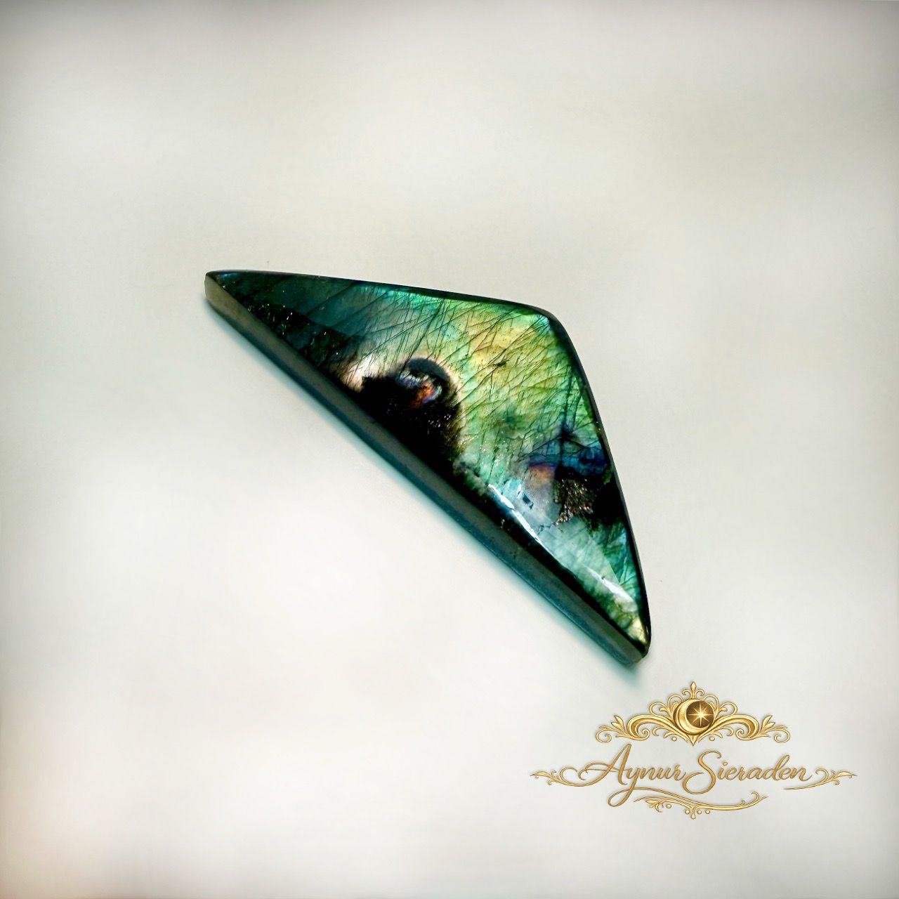 Handgeslepen driehoekige labradoriet cabochon voor exclusieve maatwerk sieraden.