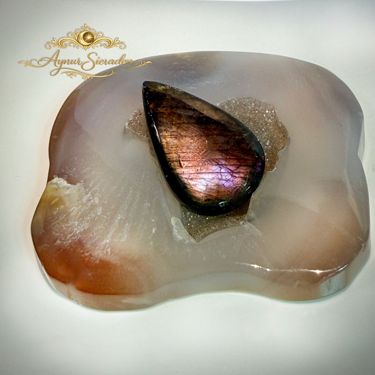 Druppelvormige labradoriet cabochon met roze en paarse glans.