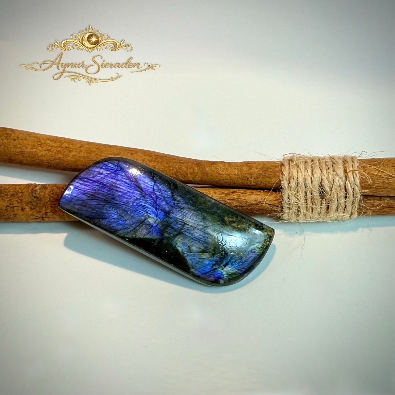 Langwerpige labradoriet cabochon met paarse en blauwe vuurglans.