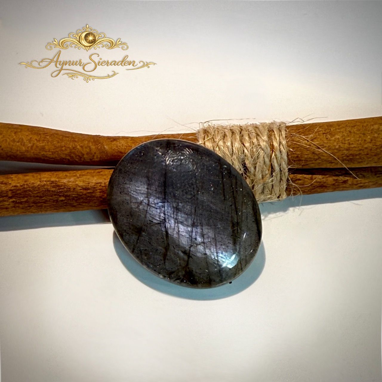 Donkere ovale labradoriet cabochon met subtiele blauwe glans.