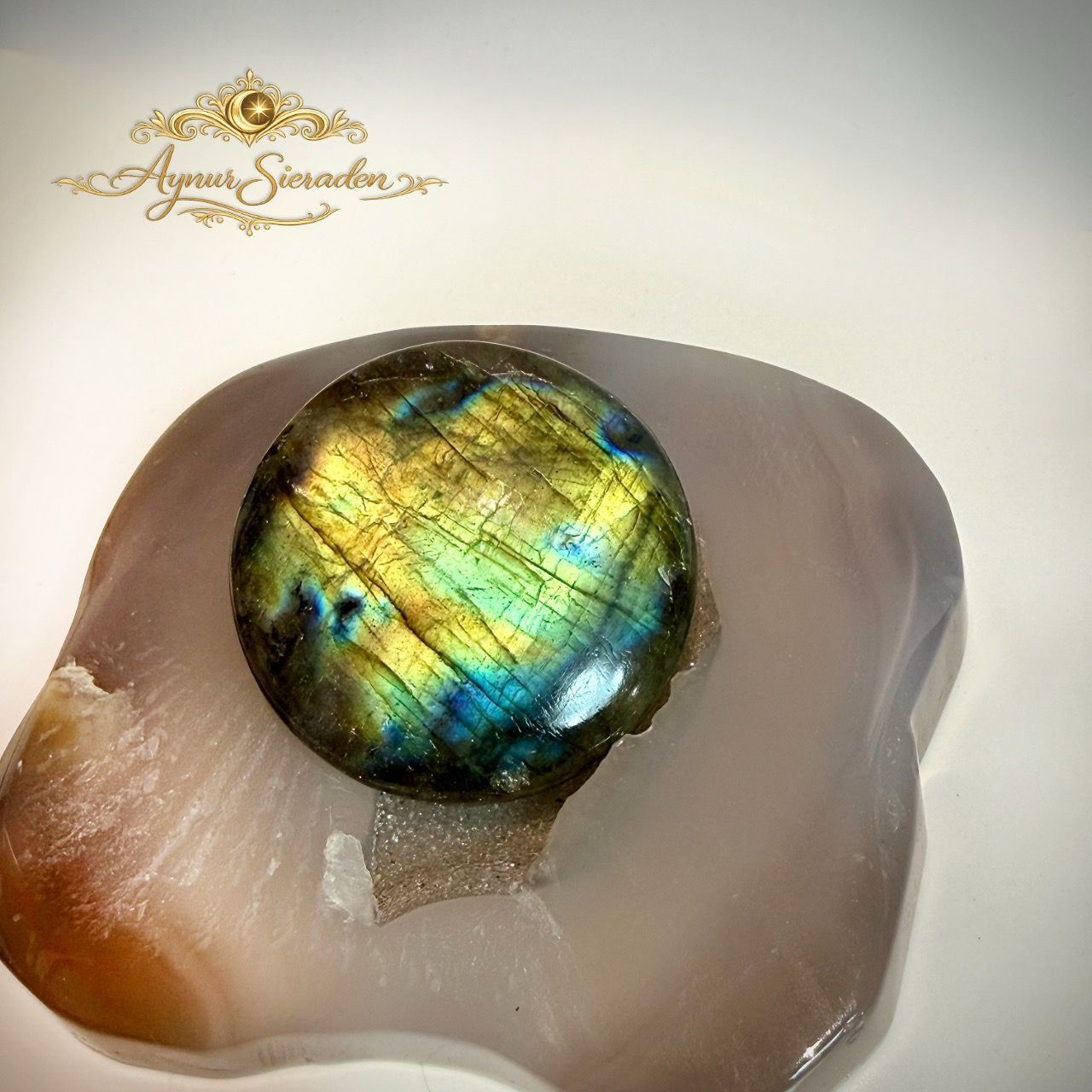 Ronde labradoriet cabochon met goudgroene en blauwe glans.