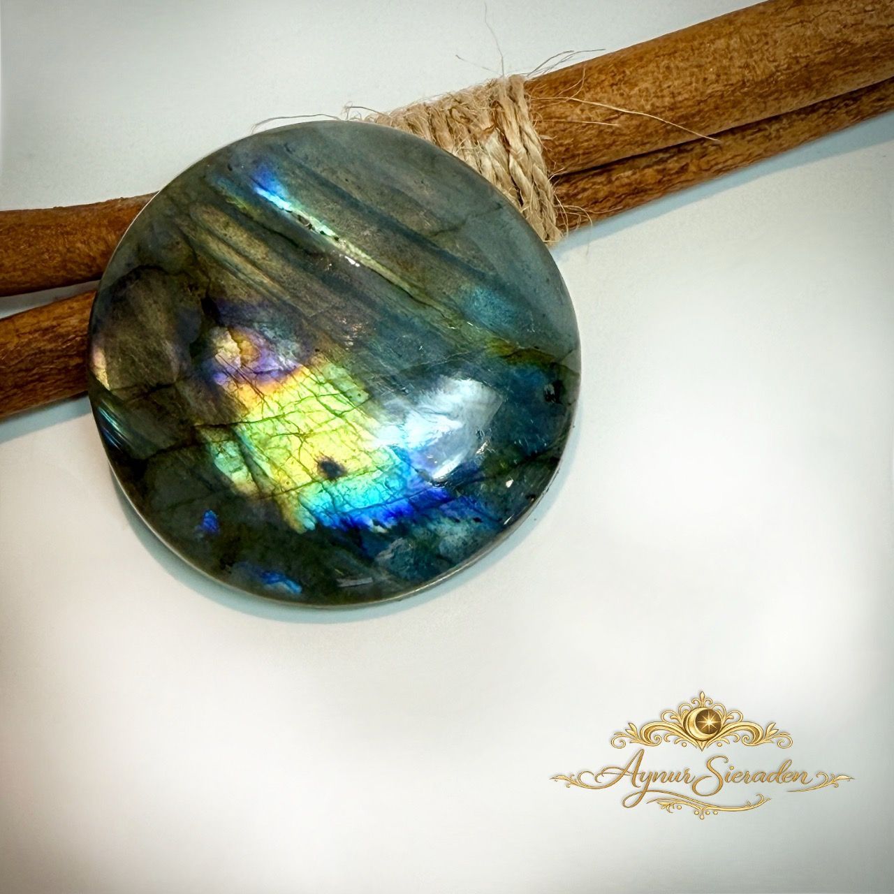 Ronde labradoriet cabochon met blauwe, gouden en groene lichtreflecties.