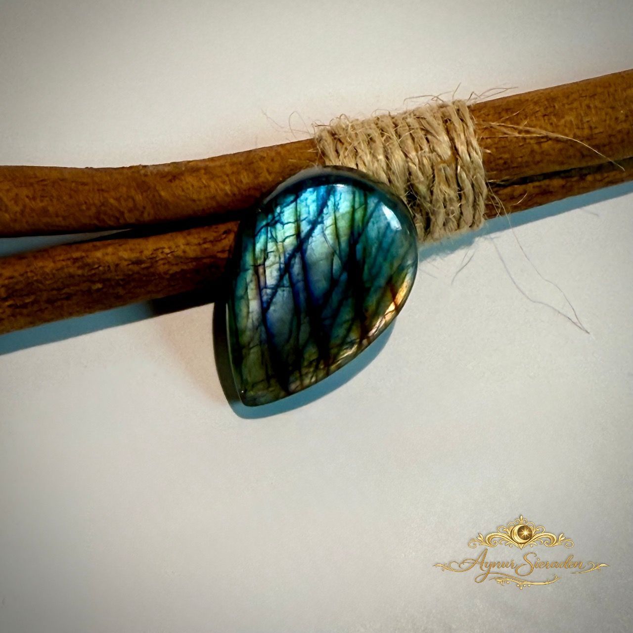Druppelvormige labradoriet cabochon met blauwe glans op natuurlijke houten achtergrond