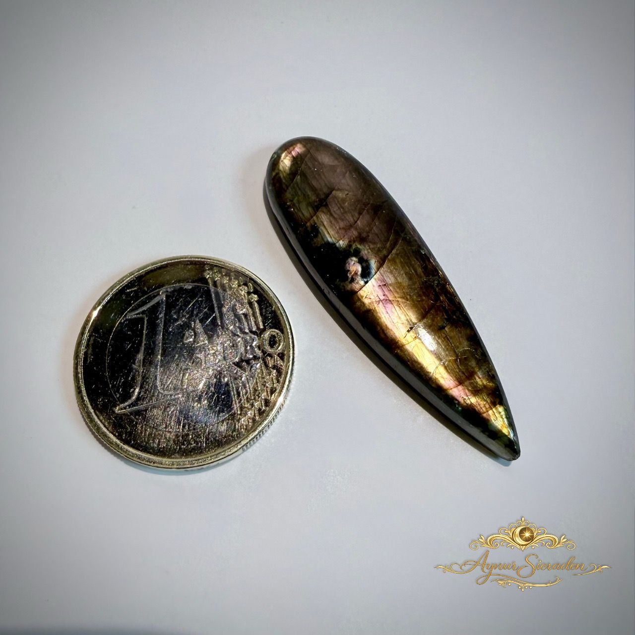 Labradoriet cabochons met natuurlijke glans naast munt ter grootte vergelijking