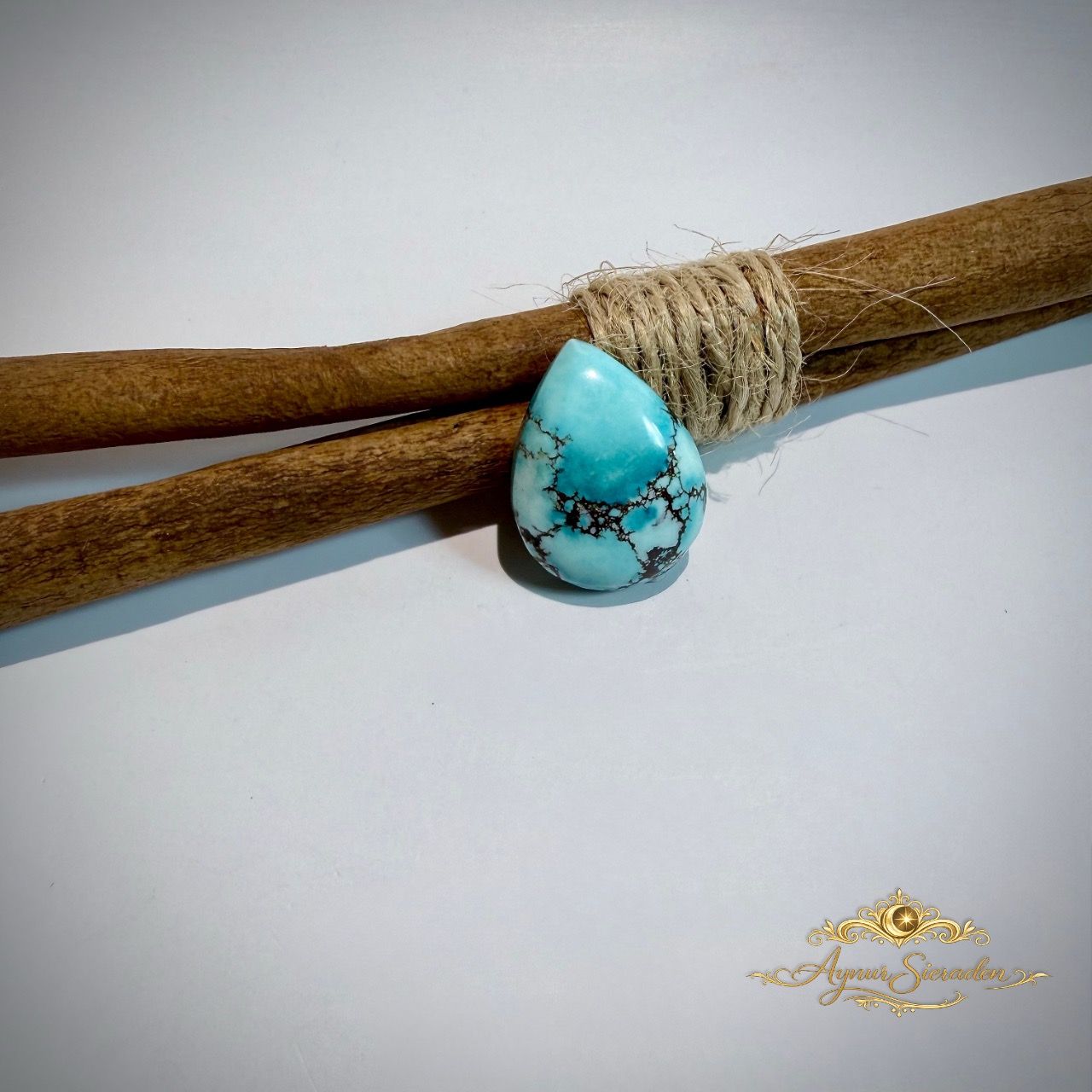 Lichtblauwe druppelvormige turkoois cabochon met donkere natuurlijke matrix.