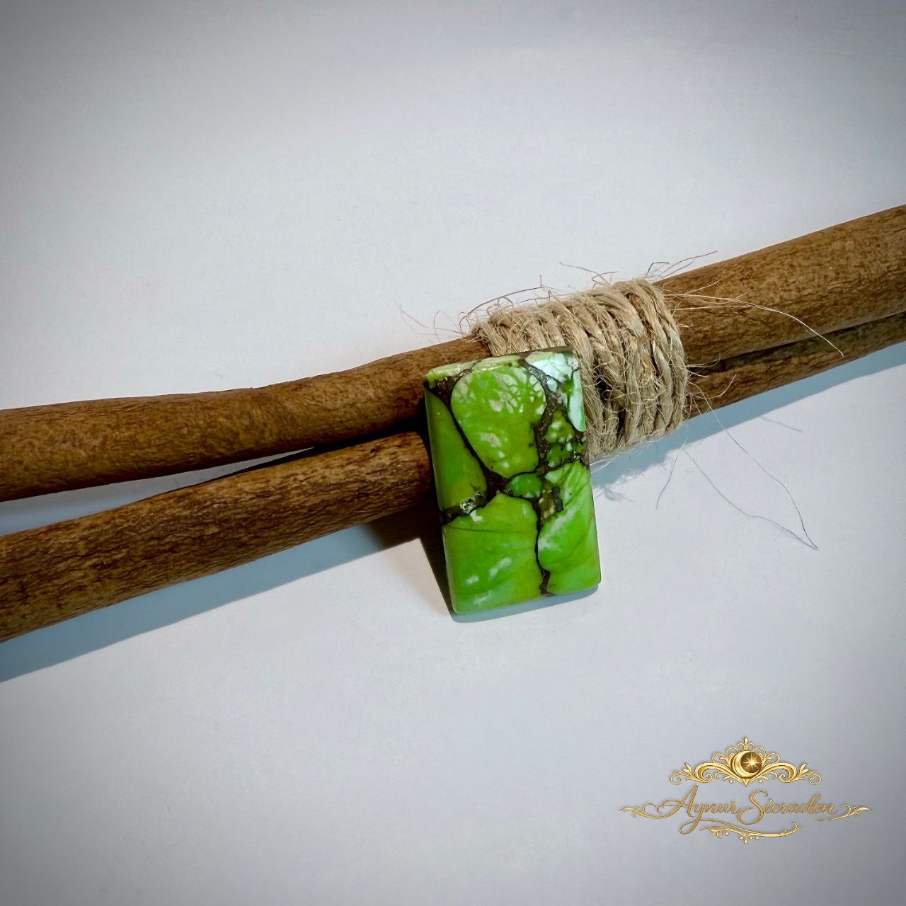 Rechthoekige groene turkoois cabochon met donkere matrix op houten takken