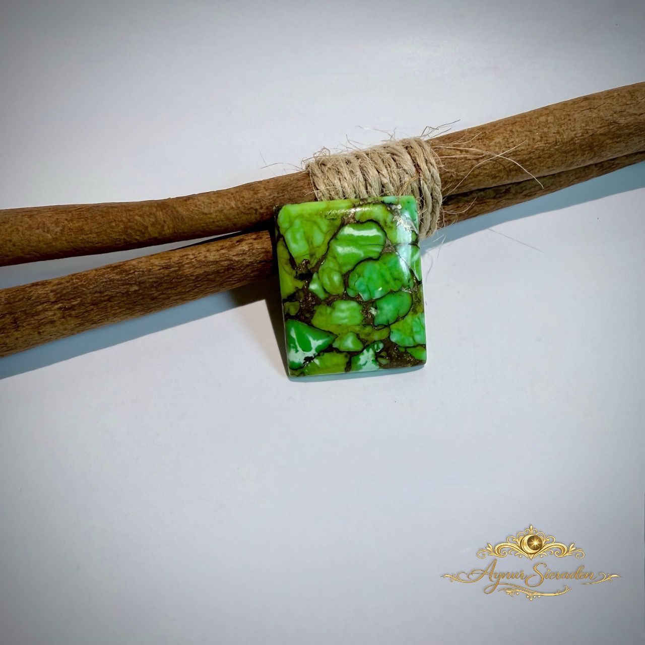 Groene rechthoekige turkoois cabochon met donkere natuurlijke matrix op lichte achtergrond.
