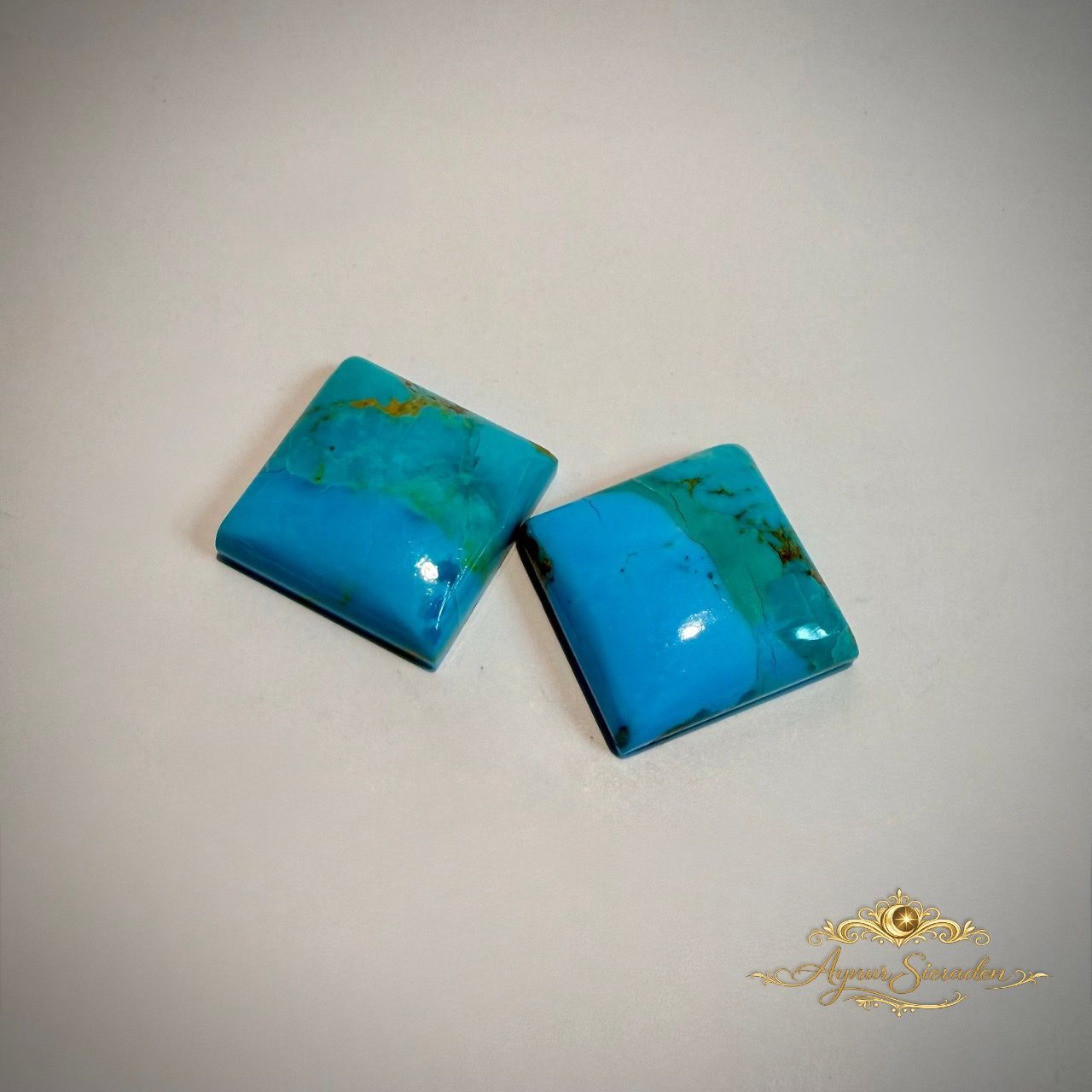 Set van twee vierkante lichtblauwe turkoois cabochons op lichte achtergrond.
