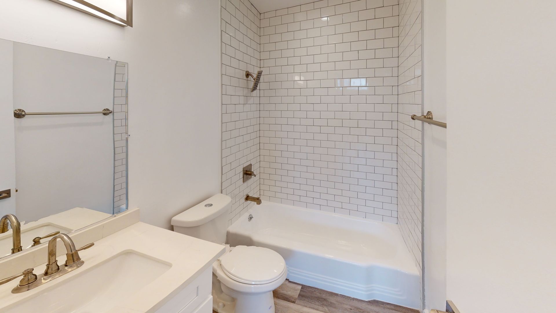 White bathroom with tiled shower, toilet, sink with mirror, and towel rack.