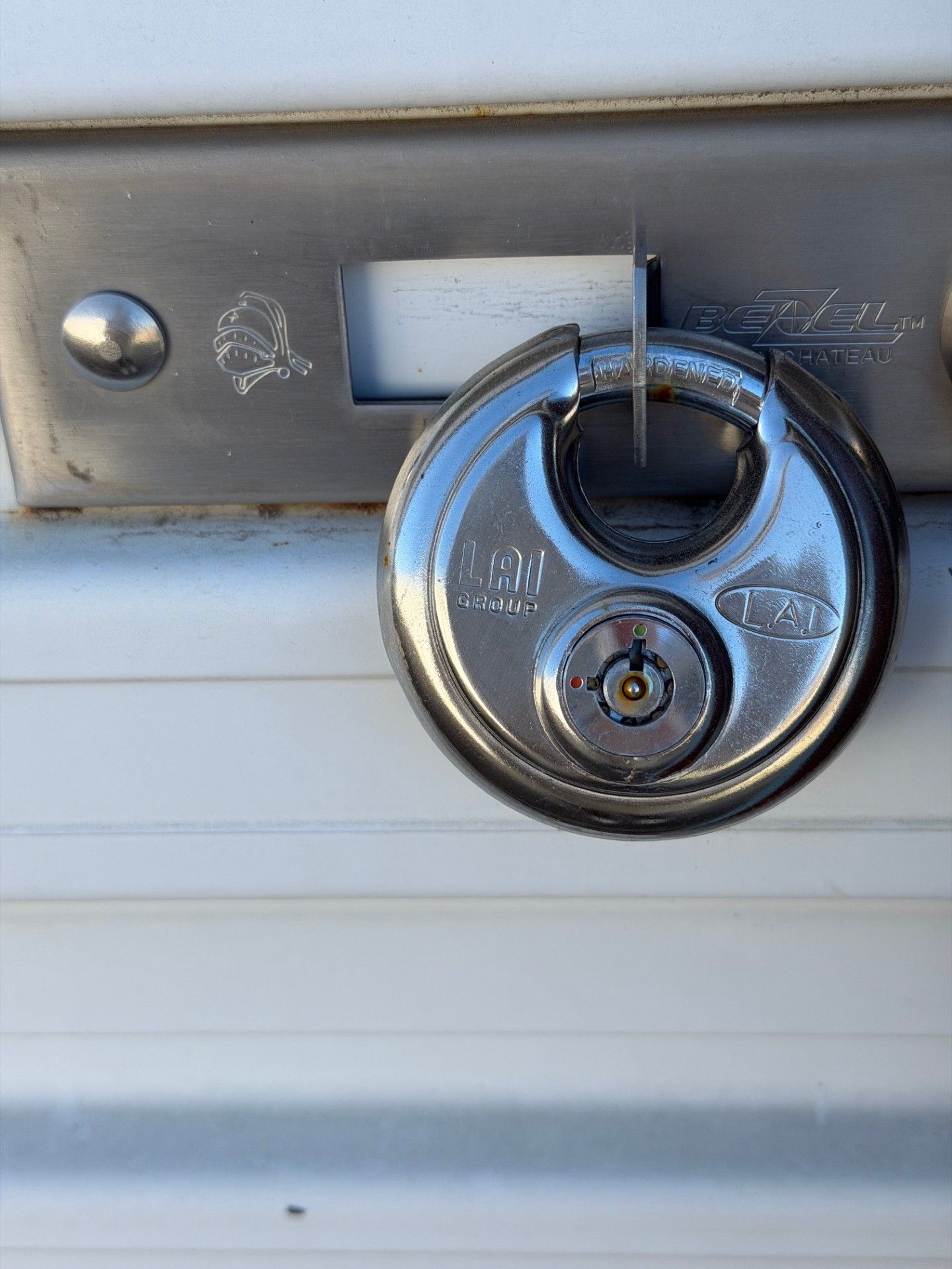 Silver disc padlock securing a white storage unit door.