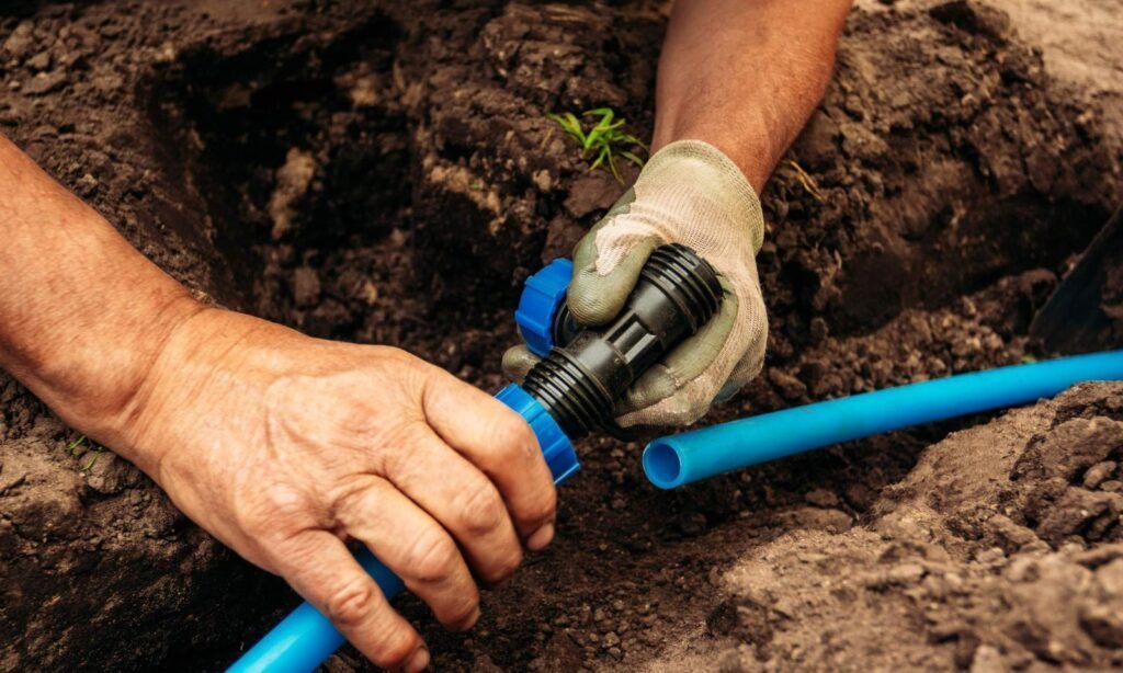 A man is installing a hose in the dirt.