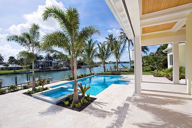 There is a large swimming pool in the backyard of a house.