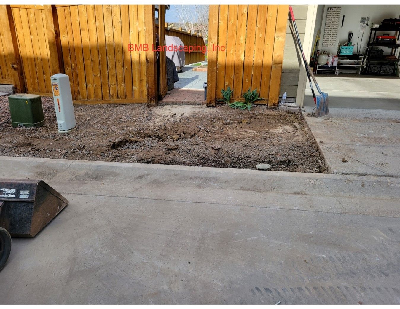 A concrete driveway with a wooden fence in the background