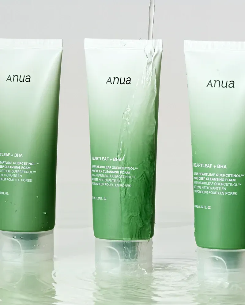 Three green bottles of anua are sitting on a table