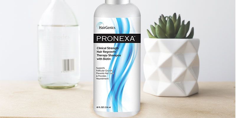 A bottle of pronexa shampoo is sitting on a wooden table next to a potted plant.