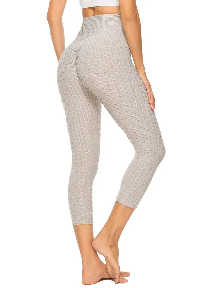A woman is wearing a white top and gray leggings.