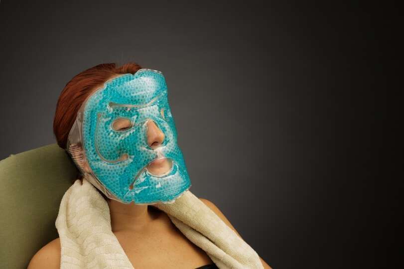 A woman is wearing a blue gel mask on her face.