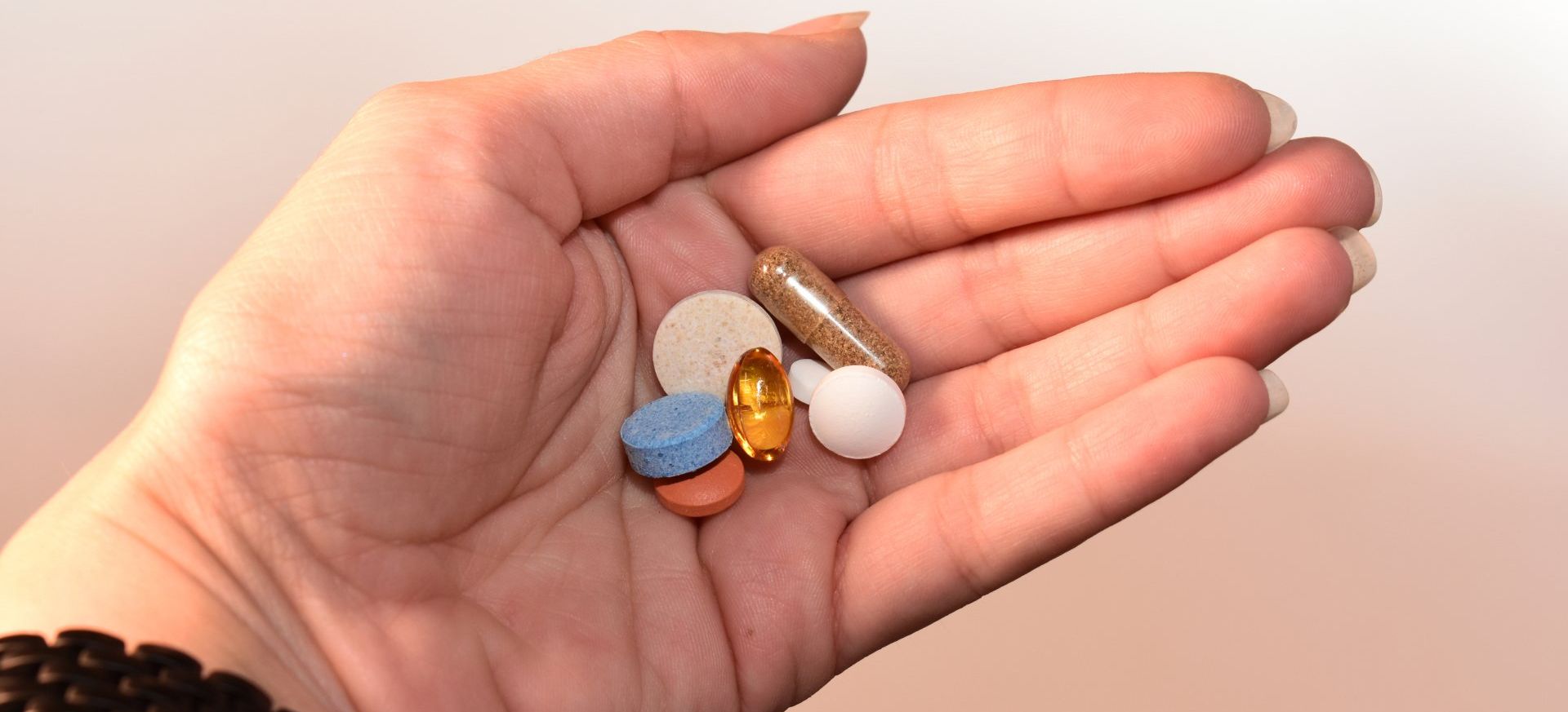 a person is holding a handful of pills in their palm .