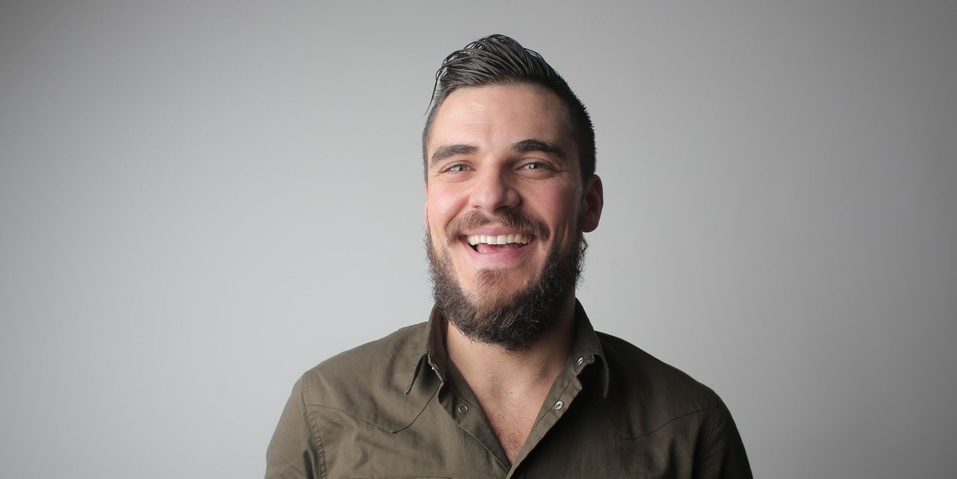 a man with a beard is smiling and looking at the camera .