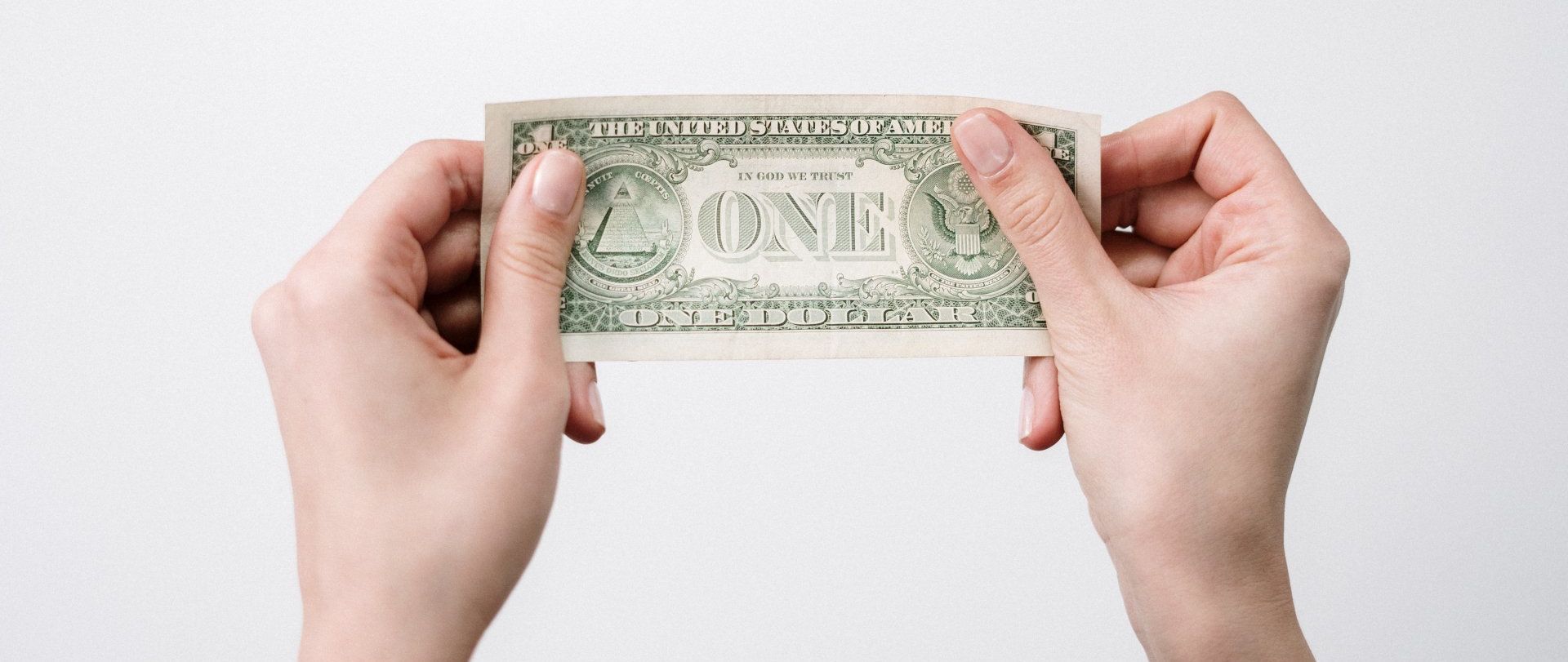 a person is holding a dollar bill in their hands .