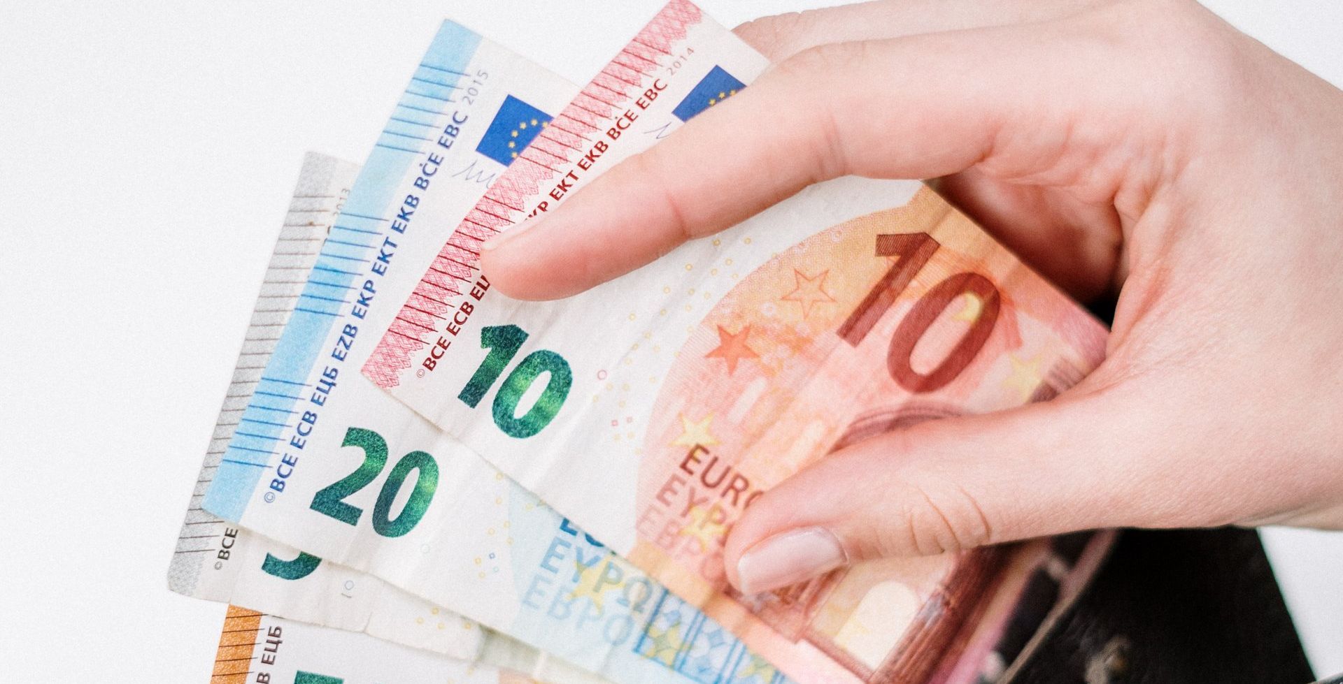 a person is holding a stack of euro bills in their hand .