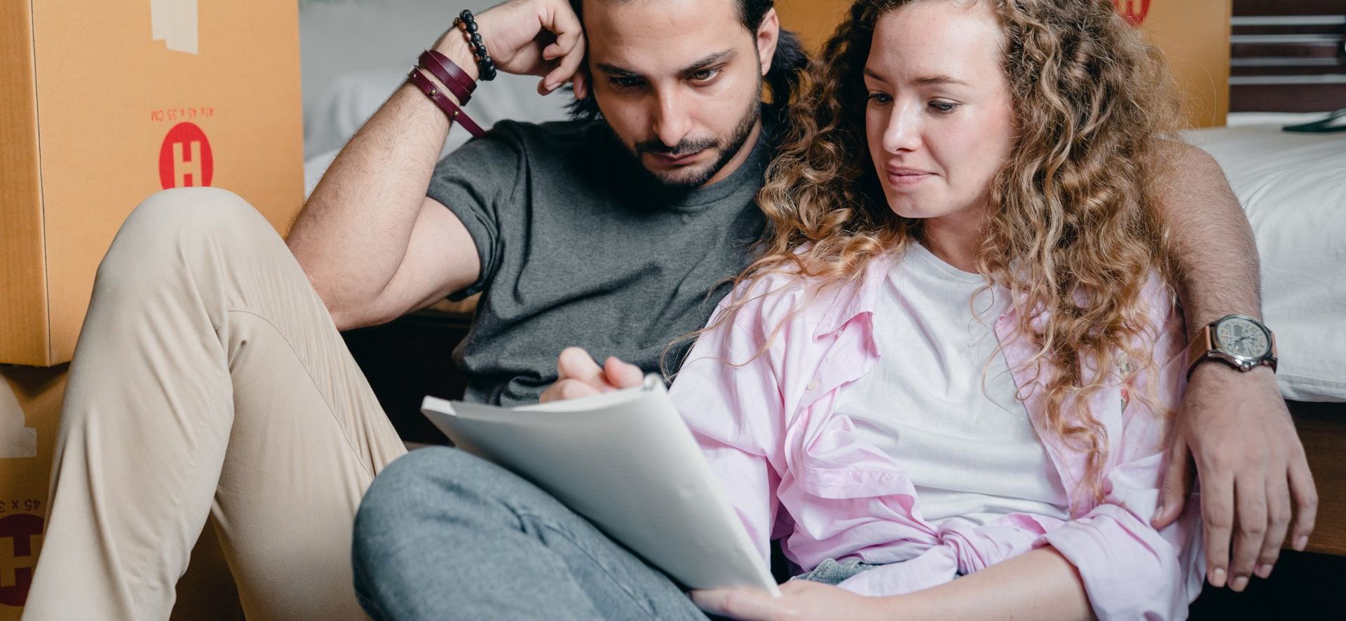 a man and a woman are sitting on the floor looking at a tablet .
