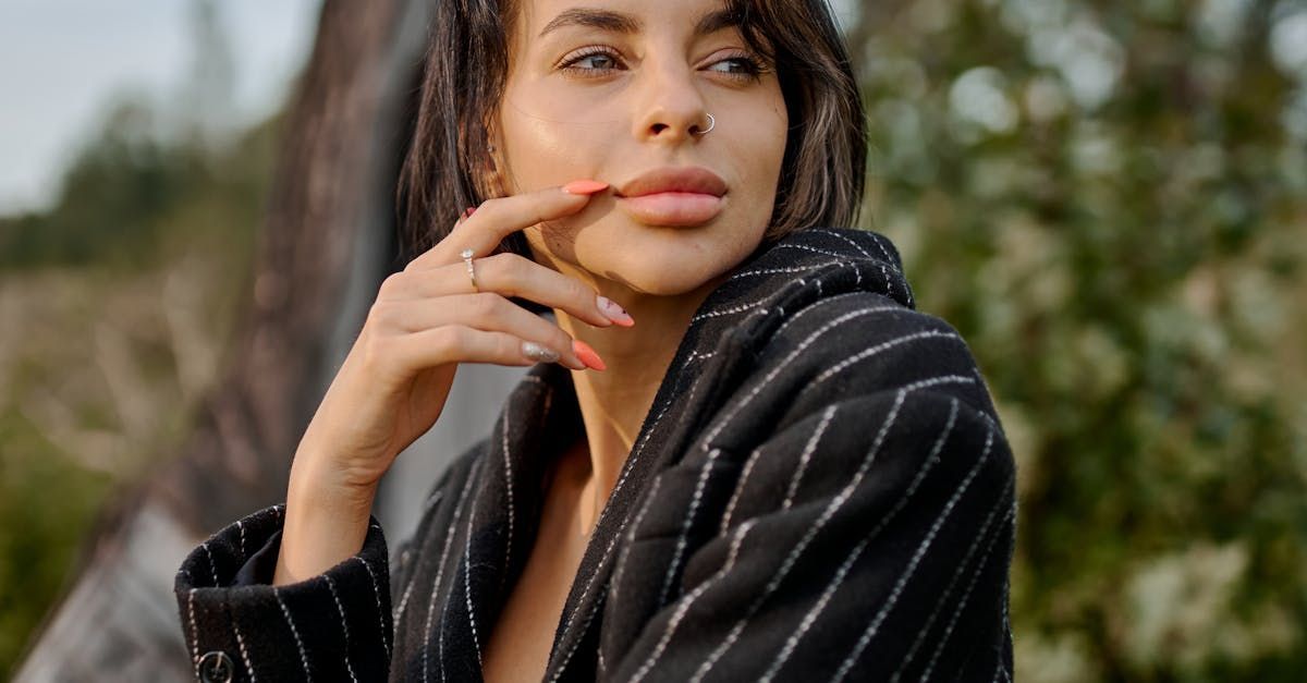 A woman in a striped jacket is holding her hand to her face.