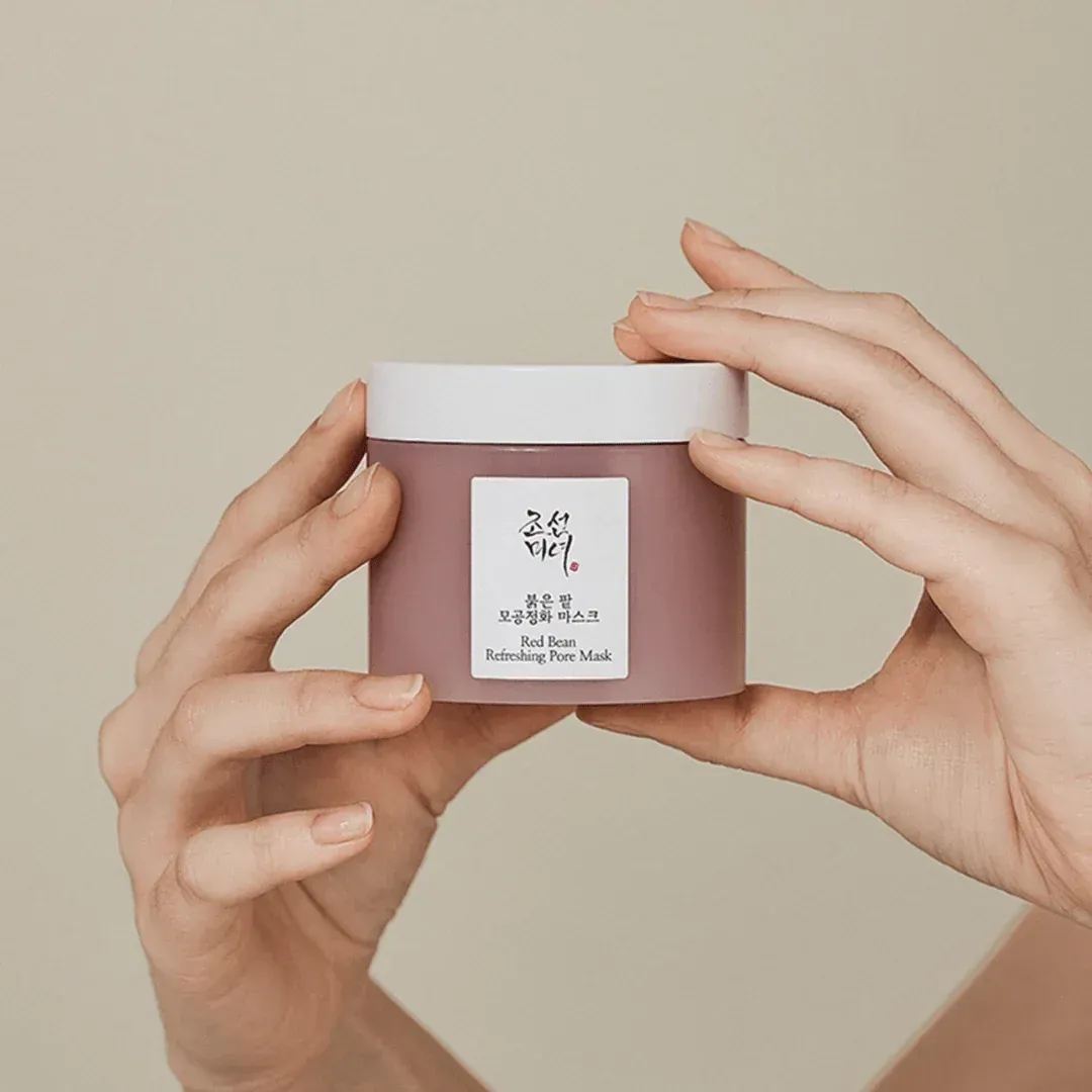 A person is holding a jar of lotion in their hands.