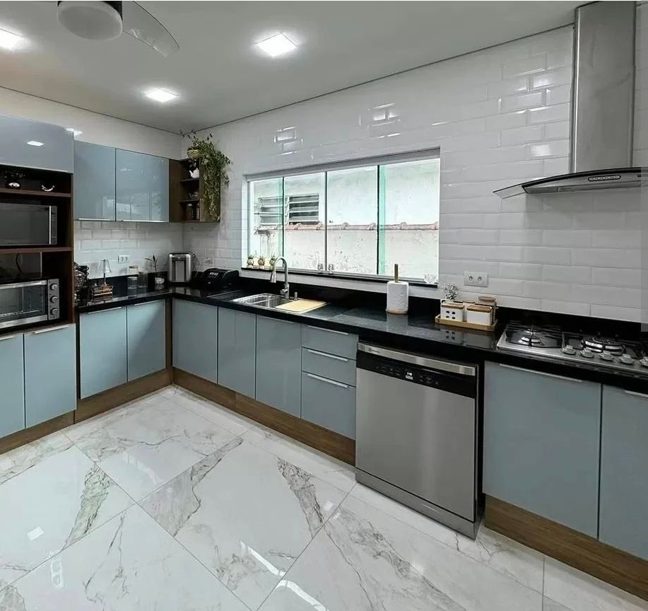 Cocina moderna con gabinetes azul claro, encimeras negras, salpicadero de azulejos blancos y electrodomésticos