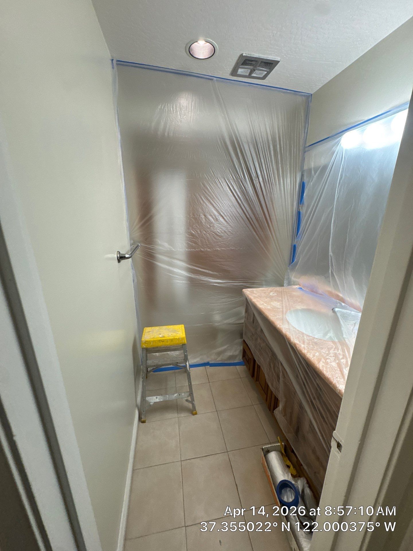 Plastic-covered room under renovation with a small step stool and a covered counter.