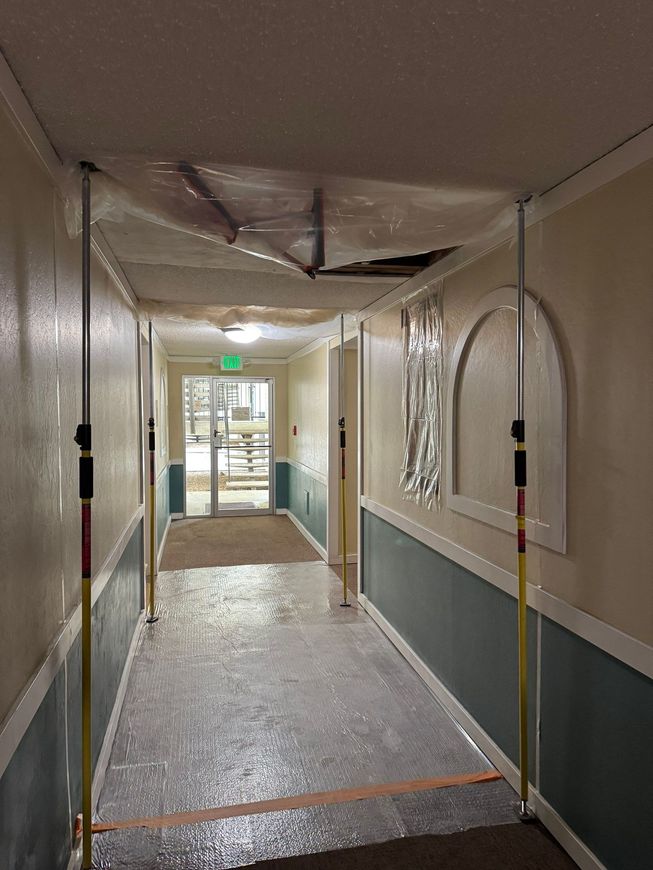 Narrow hallway with blue walls, textured floor, and exit door at the end.