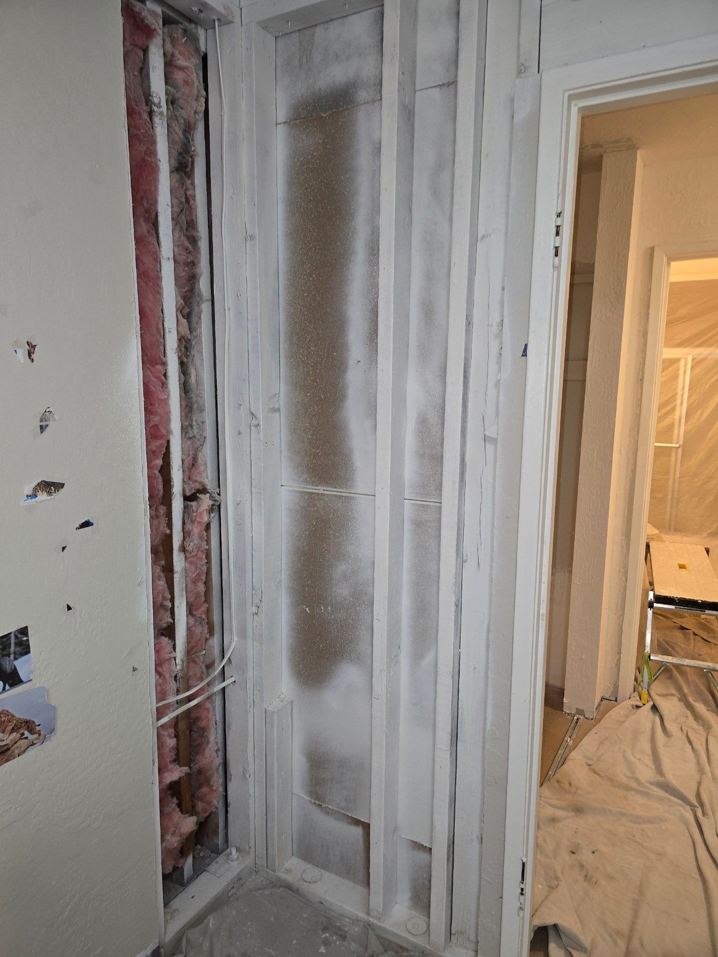 Partially finished doorway with exposed framing, white drywall, and construction materials in a hallway