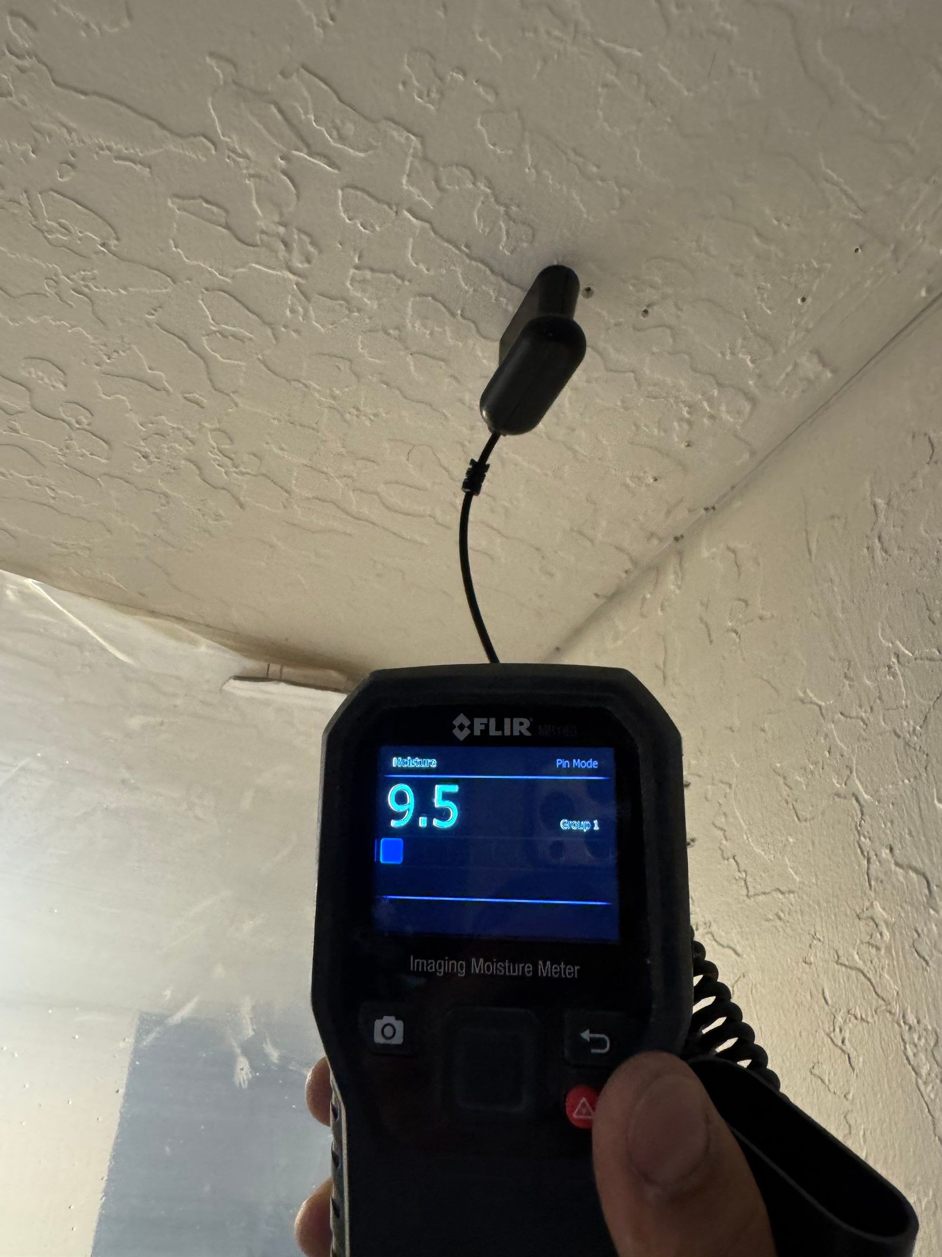 Infrared thermometer aimed at a ceiling, displaying 9.5 on its screen.