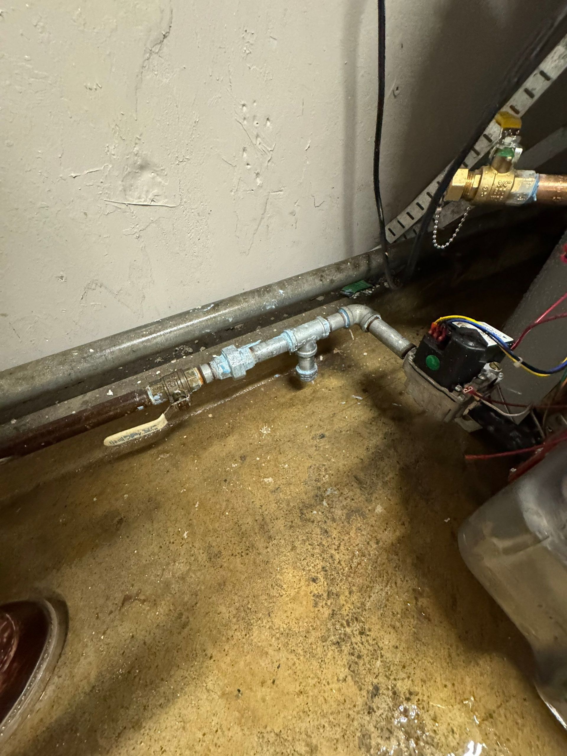 Copper plumbing pipes inside a wall cavity, including a vertical pipe with an elbow joint.