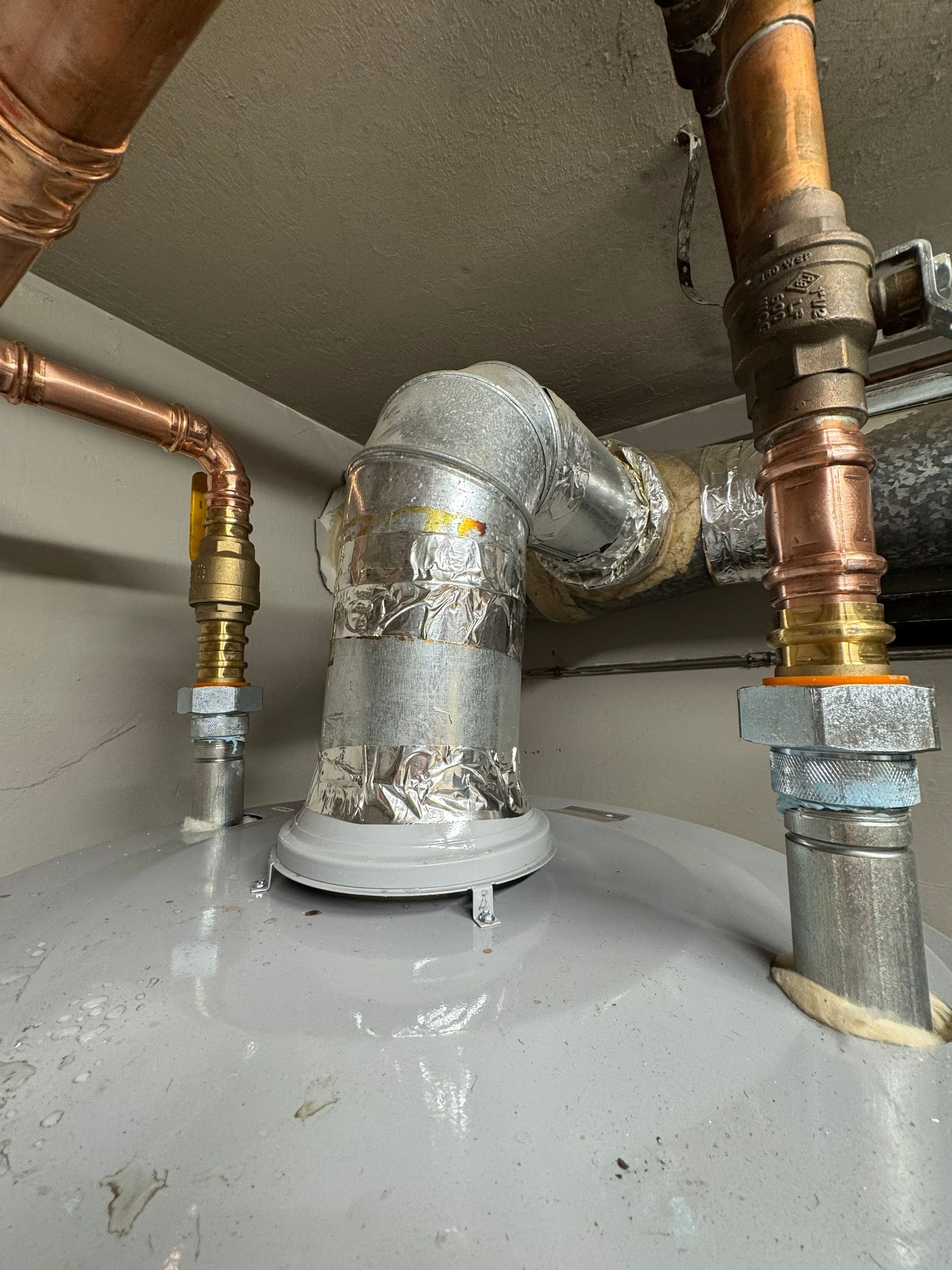 Exposed pipes and ductwork in a damaged ceiling above a water-stained room corner