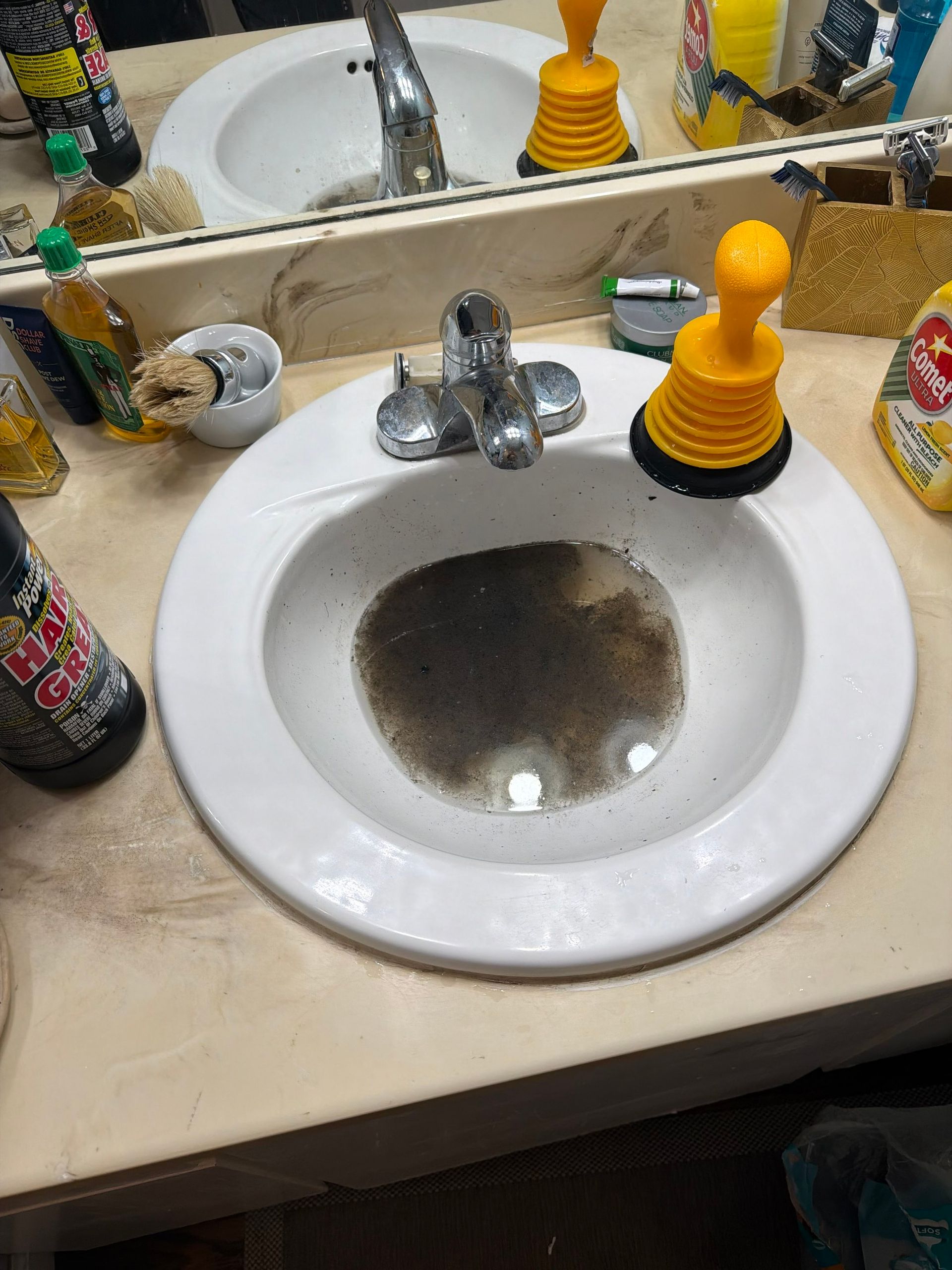 Dirty bathroom sink with chrome faucet and yellow soap dispenser on a beige countertop