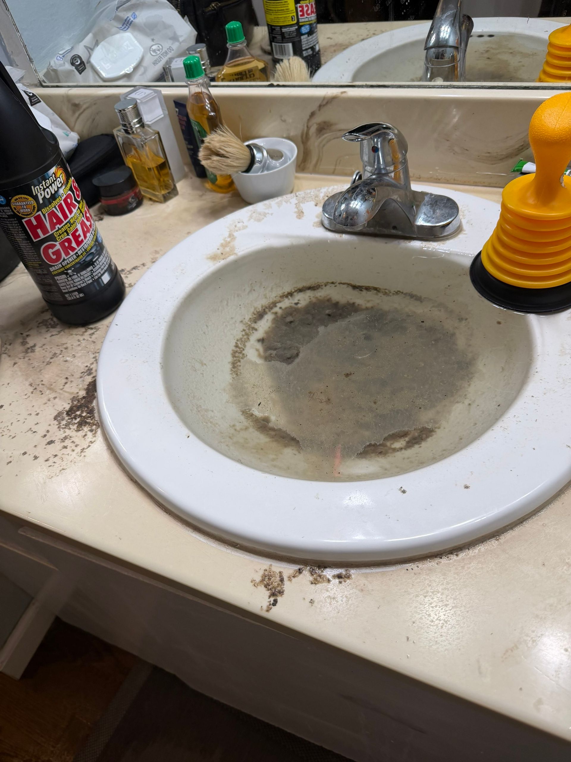 Dirty bathroom sink with a clogged drain and soap dispenser on the counter