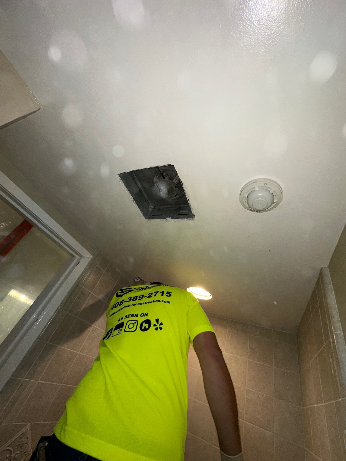 Exposed plumbing and pipes inside a wall opening above a baseboard, with wood framing and drywall cutout.