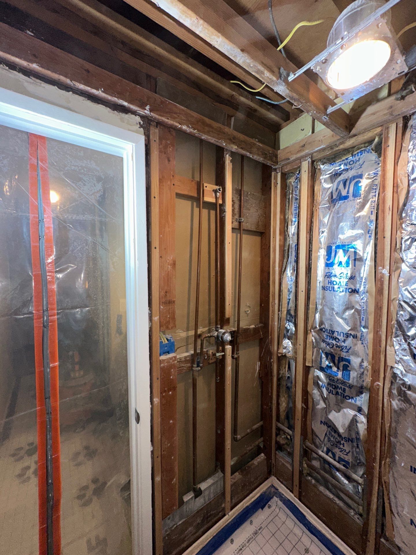 Copper plumbing pipes inside a wall cavity, including a vertical pipe with an elbow joint.