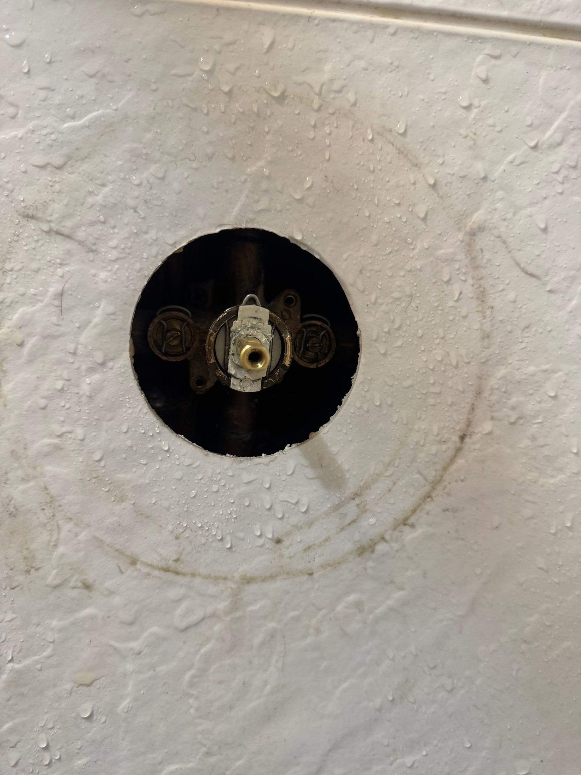 Close-up of corroded copper pipes and a damp wooden wall inside a cramped utility space