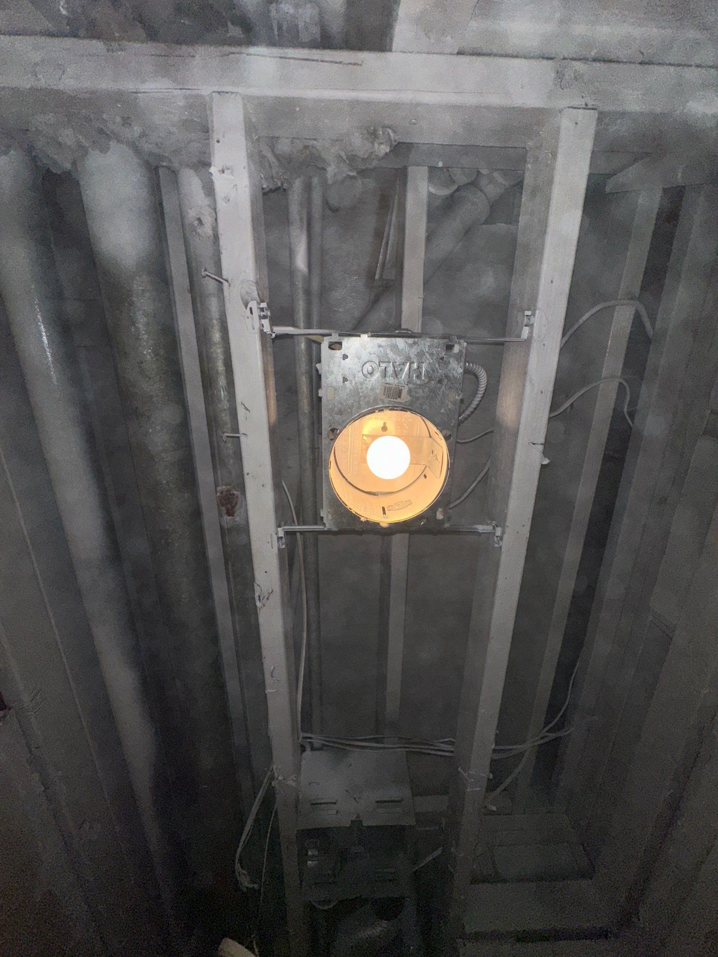 Exposed pipes and ductwork in a damaged ceiling above a water-stained room corner
