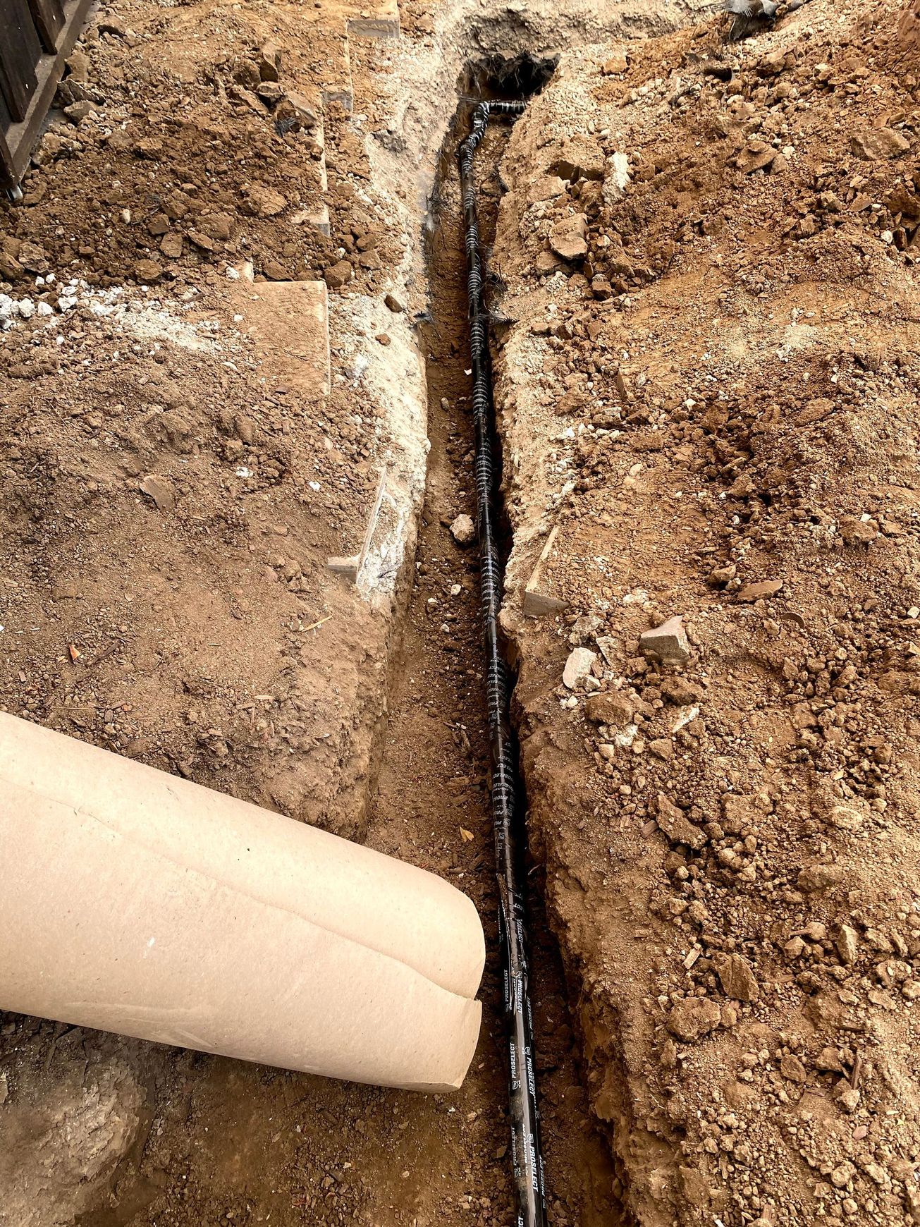 Exposed plumbing and wood framing inside a wall cavity with black pipe and a copper tube.