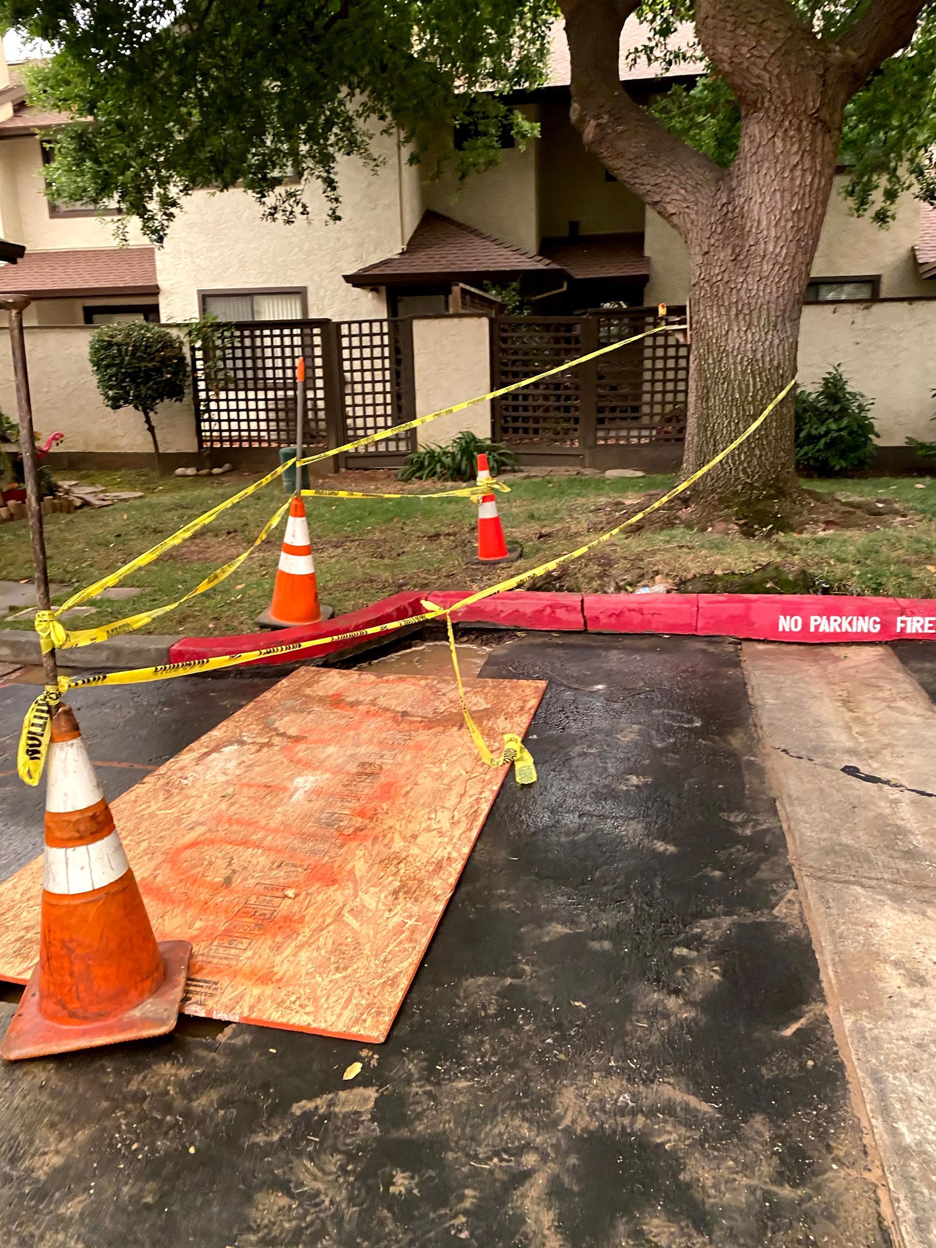 Narrow hallway with a rolling cart, tools, orange cones, and plastic sheeting covering the far end
