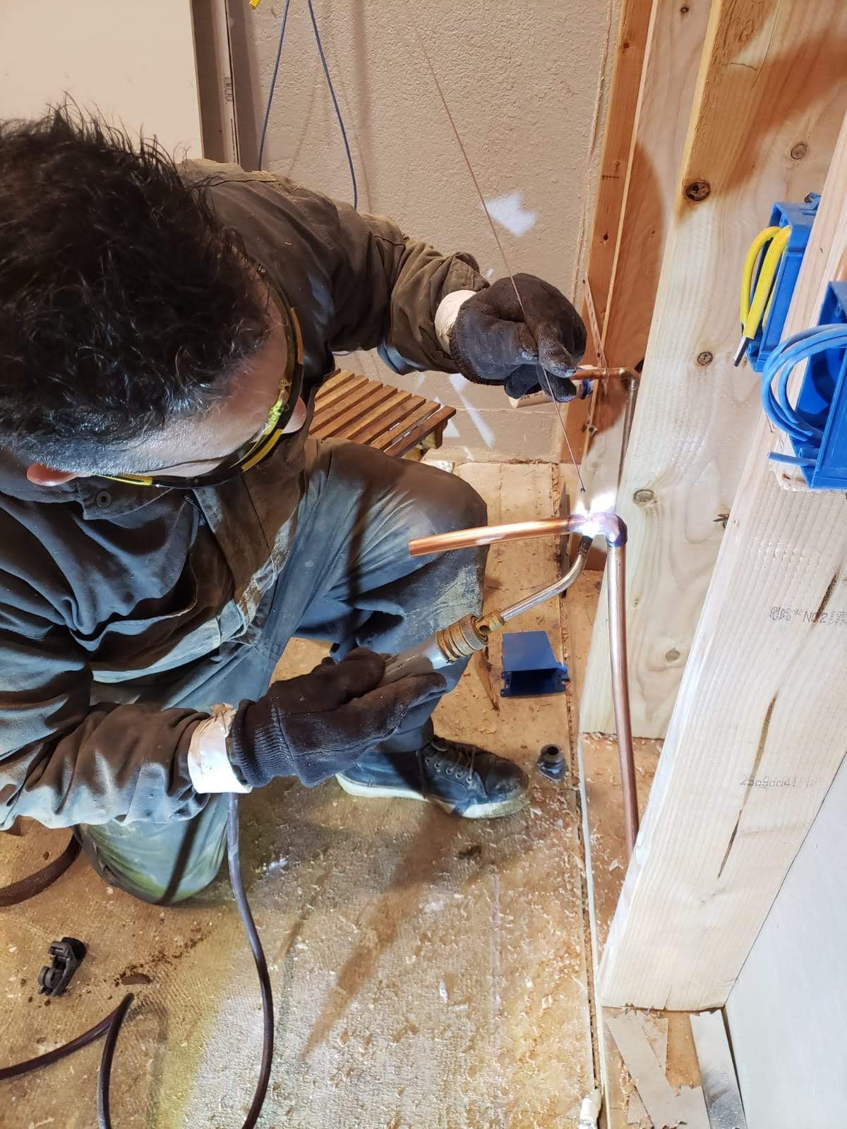 Interior wall renovation with exposed insulation, a window, and a worker installing drywall panels