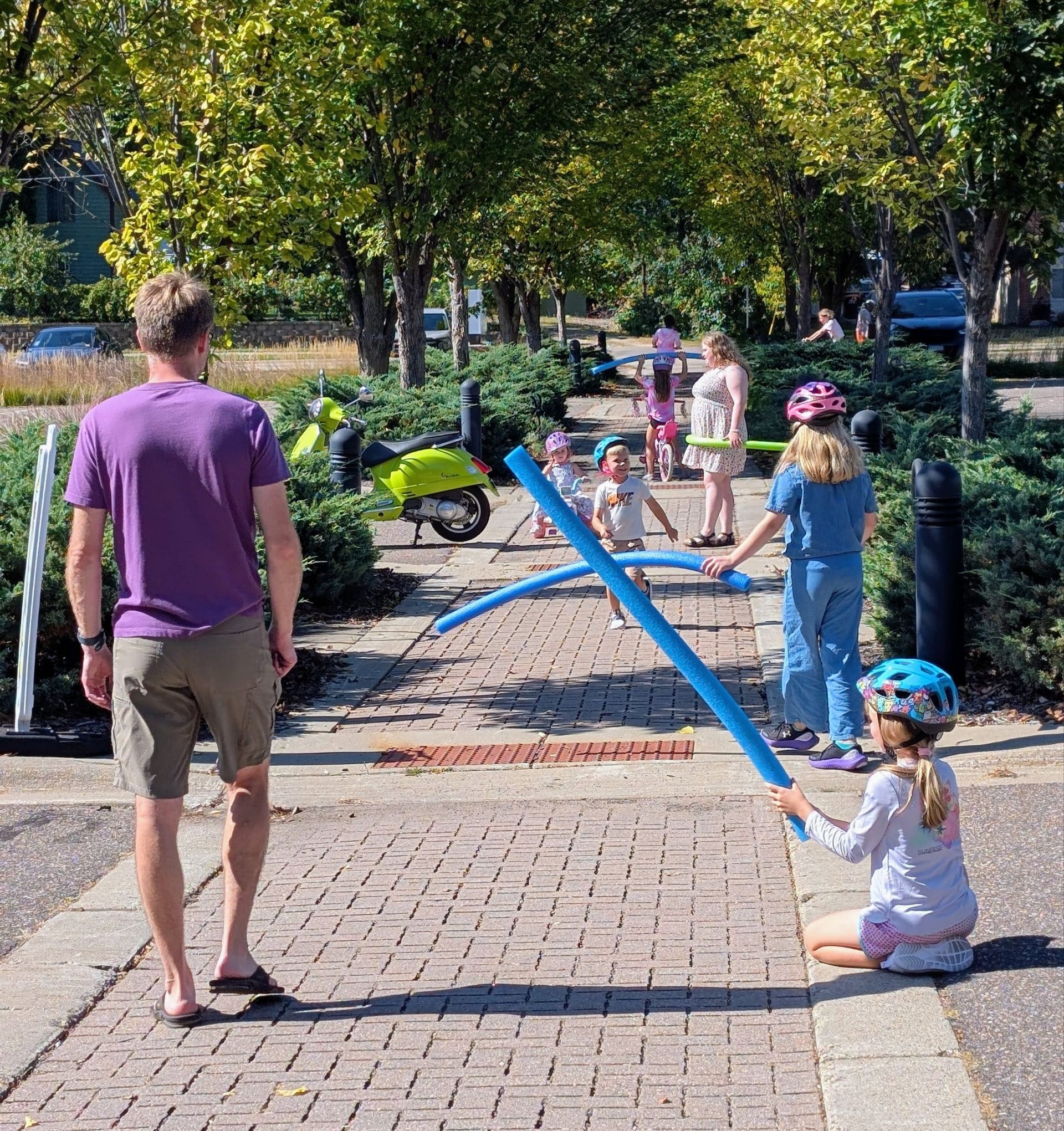 kids with water noodles creating obstacle course for bikers