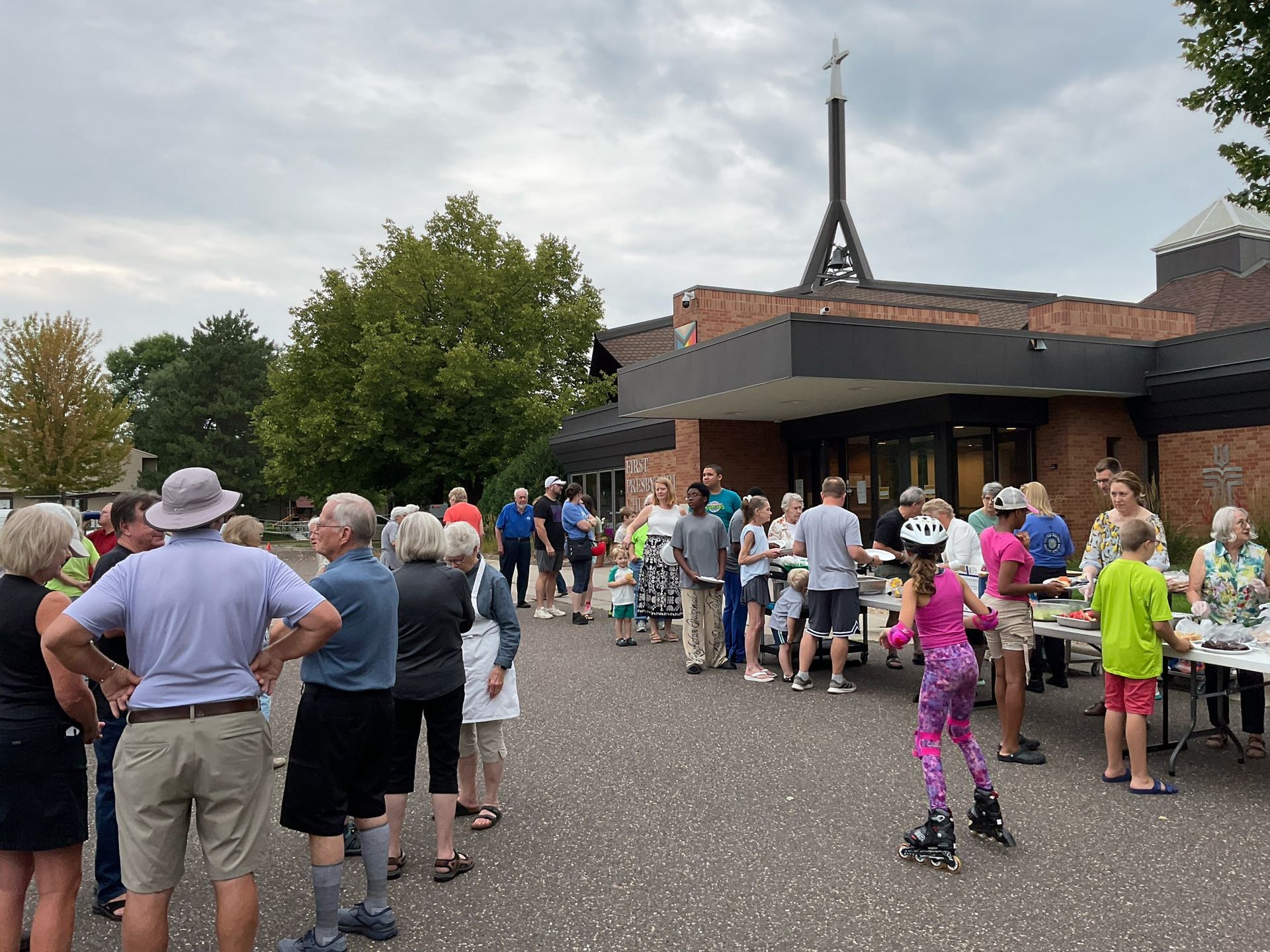 People are standing in buffet line for summer community picnic.